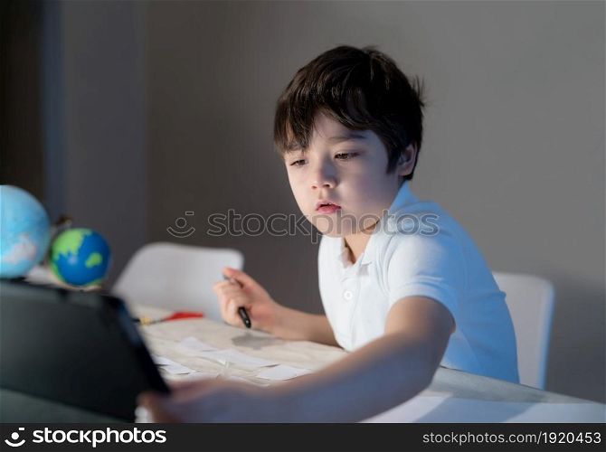 School kid using tablet for his homework,Child boy doing homework by using digital tablet searching information on internet after back from school,E-learning, Home schooling education concept
