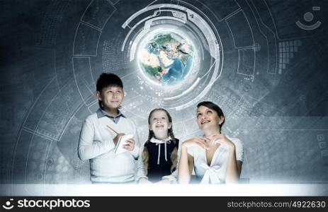 School lesson. Young teacher and school children examining hologram. Elements of this image are furnished by NASA