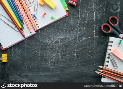 School, office supplies on a chalkboard background. Free space for text. School and office supplies on a chalkboard background. Free space for text. Top view