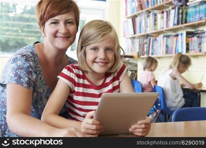 School Pupil With Teacher Using Digital Tablet Computer In Classroom