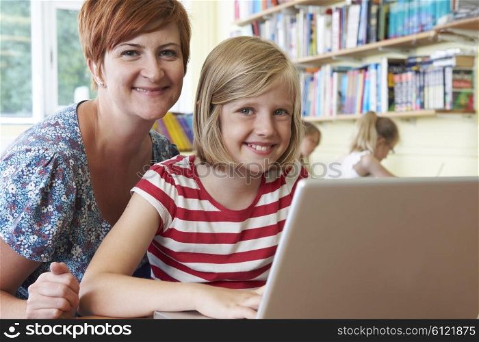 School Pupil With Teacher Using Laptop Computer In Classroom