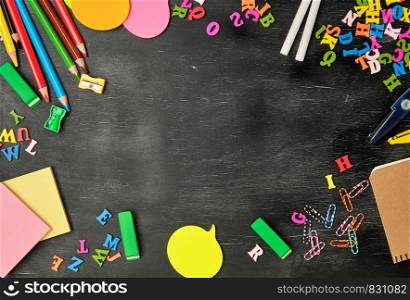school supplies: multicolored wooden pencils, notebook, paper stickers, paper clips, pencil sharpener and white chalk, copy space