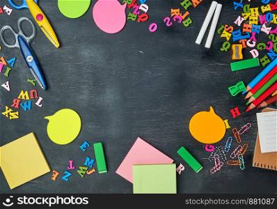 school supplies: multicolored wooden pencils, notebook, paper stickers, paper clips, pencil sharpener and white chalk, copy space