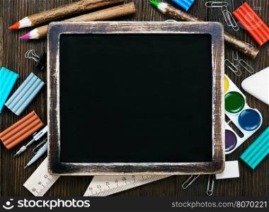 school supplies on a table, black board and school supplies