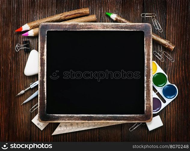 school supplies on a table, black board and school supplies