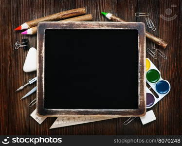 school supplies on a table, black board and school supplies