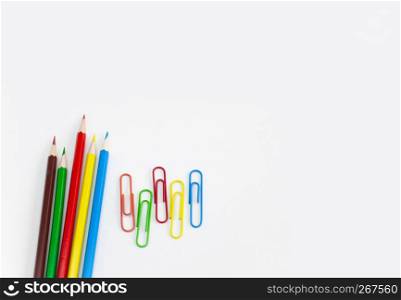 School supplies stationery concepts, Multi-colored pencils and clips on white background with copy space. View from above.