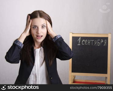 School teacher holding his head thinking that on September 1 will bring many new problems. In the background stands Board