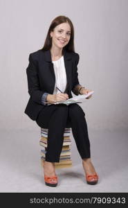 School teacher sits on a stack of books and checks notebook students.