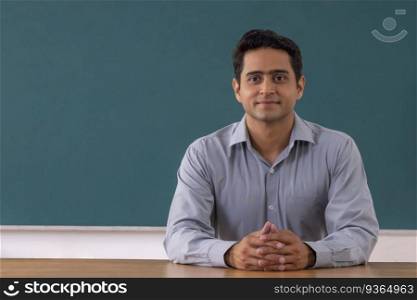 School teacher sitting in front of blackboard in classroom