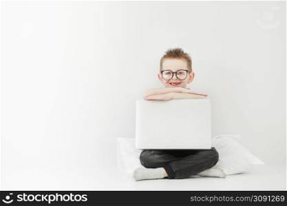 schoolboy in glasses using laptop sitting on bed. Child doing school homework and seriously and tired looking on camera.Online learning, distance lesson, education with online tutor at home isolation.. schoolboy in glasses using laptop sitting on bed. Child doing school homework and seriously and tired looking on camera.Online learning, distance lesson, education with online tutor at home isolation