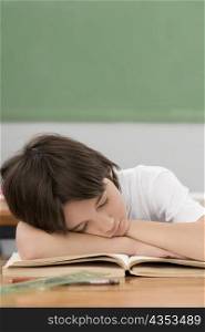 Schoolboy napping on a desk in a classroom