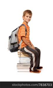 Schoolboy sitting on books isolated on a white background