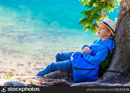 Schoolboy traveler with a rucksack resting by the lake in the Ta. Schoolboy traveler with a rucksack resting by the lake in the Tatras