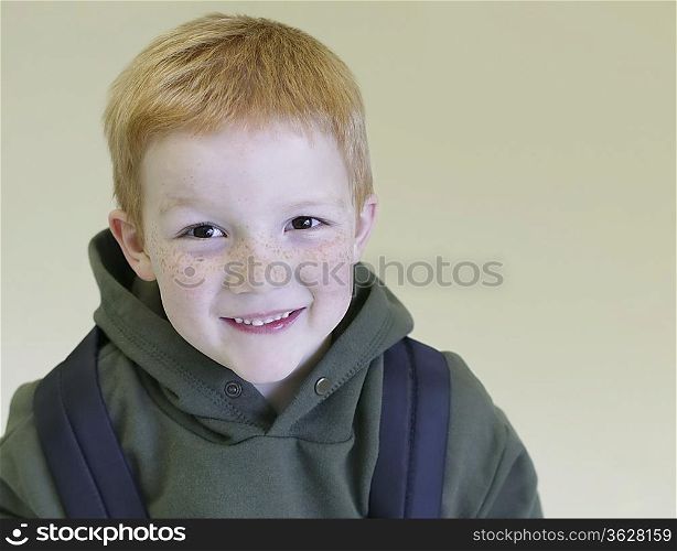 Schoolboy with redhair and freckles stands with backpack