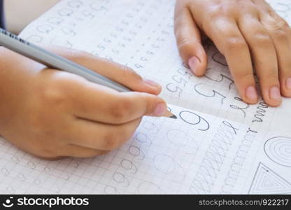 Schoolboy writing numbers close up. Pencil in the hands of children. The boy is writing.. Schoolboy writing numbers close up. Pencil in the hands of children.