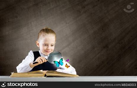 Schoolgirl at lesson. Little school girl examining butterfly with magnifying glass