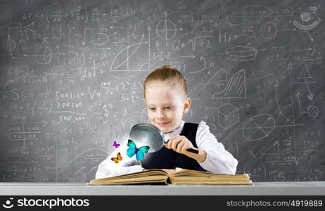 Schoolgirl at lesson. Little school girl examining butterfly with magnifying glass