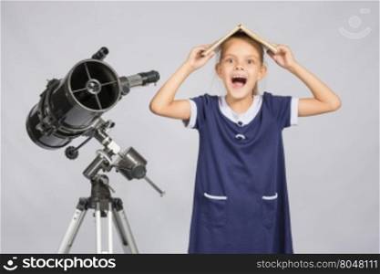 Schoolgirl covered her head with a textbook and cry looking at the frame, standing at the telescope