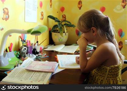 schoolgirl learns lessons at the table in her room