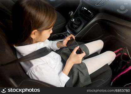 Schoolgirl using smartphone while going to school by car