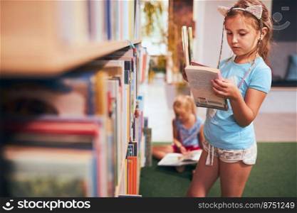 Schoolgirls looking for book for reading in school library. Students choosing books for reading. Learning from books. Back to school. Elementary education. Doing homework