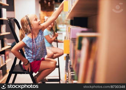 Schoolgirls looking for books in school library. Students choosing books. Elementary education. Doing homework. Learning from books. Back to school