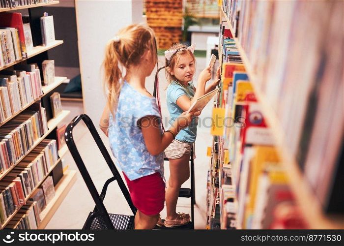 Schoolgirls looking for books in school library. Students choosing set books. Elementary education. Doing homework. Learning from books. Back to school