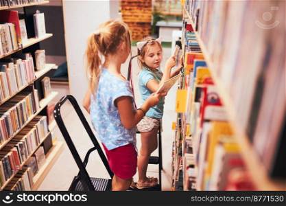 Schoolgirls looking for books in school library. Students choosing set books. Elementary education. Doing homework. Learning from books. Back to school