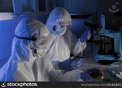 science, chemistry and people concept - close up of scientists with chemical samples in petri dish making test or research at laboratory