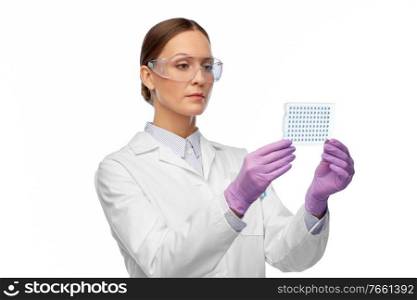 science, chemistry and people concept - young female scientist in goggles with chemical s&le or vaccine. female scientist in goggles with chemical s&le