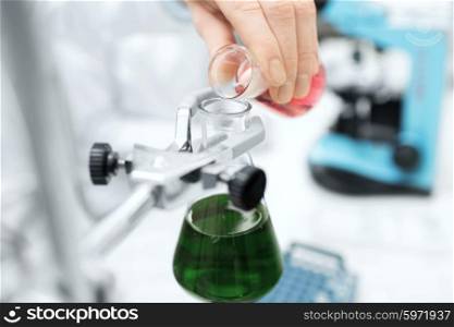 science, chemistry, biology, medicine and people concept - close up of scientist hand filling test tubes and making research in clinical laboratory