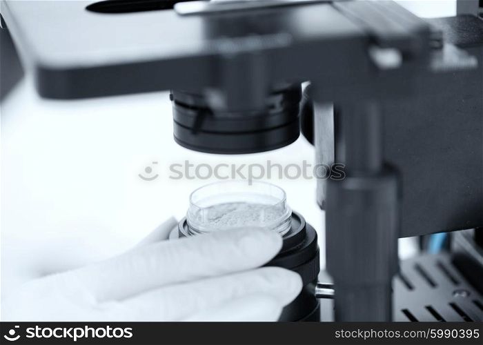 science, chemistry, biology, medicine and people concept - close up of scientist hands with microscope and powder test sample making research in clinical laboratory