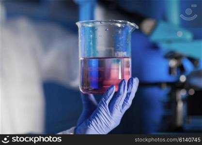 science, chemistry, biology, medicine and people concept - close up of scientist hand holding glass with chemical sample and making test or research in clinical laboratory