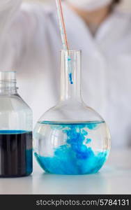 science, chemistry, biology, medicine and people concept - close up of young female scientist with pipette and flask making test or research in clinical laboratory