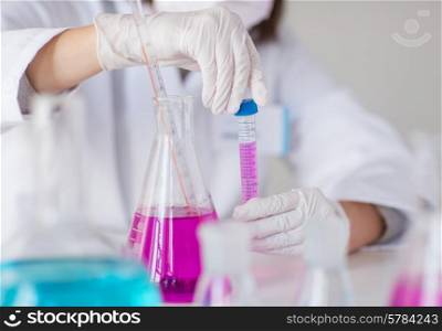 science, chemistry, biology, medicine and people concept - close up of young female scientist closing tube with sample and flask making test or research in clinical laboratory