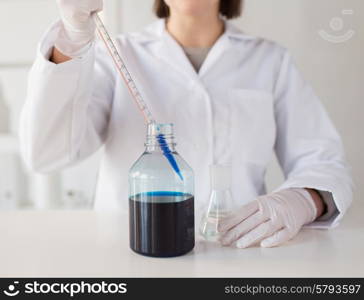 science, chemistry, biology, medicine and people concept - close up of young female scientist with pipette and flask making test or research in clinical laboratory