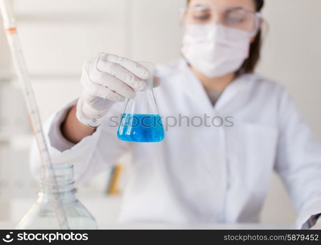 science, chemistry, biology, medicine and people concept - close up of young female scientist with flask making test or research in clinical laboratory