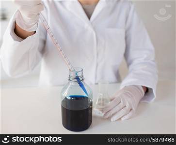 science, chemistry, biology, medicine and people concept - close up of young female scientist with pipette and flask making test or research in clinical laboratory