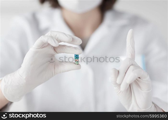 science, chemistry, biology, medicine and people concept - close up of young female scientist or doctor holding pill and pointing finger up in laboratory