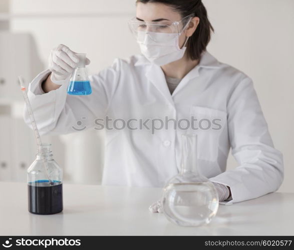 science, chemistry, biology, medicine and people concept - close up of young female scientist with pipette and flask making test or research in clinical laboratory