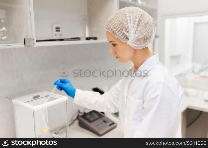 science, chemistry, industry and people concept - woman scientist or chemist adding sulphuric acid into flask on scale at laboratory. woman with sulphuric acid and scale at laboratory