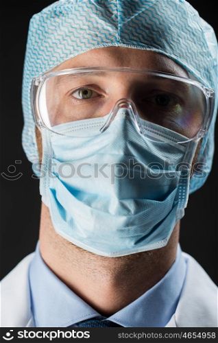 science, chemistry, medical equipment and people concept - close up of scientist face in goggles, protective mask and hat over black background