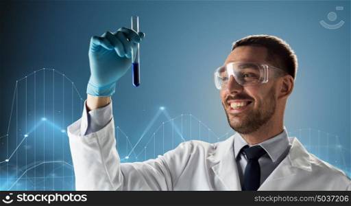 science, chemistry, medical research and people concept - young smiling scientist in safety glasses with test tube and diagram projection over blue background. scientist in goggles with test tube and diagram