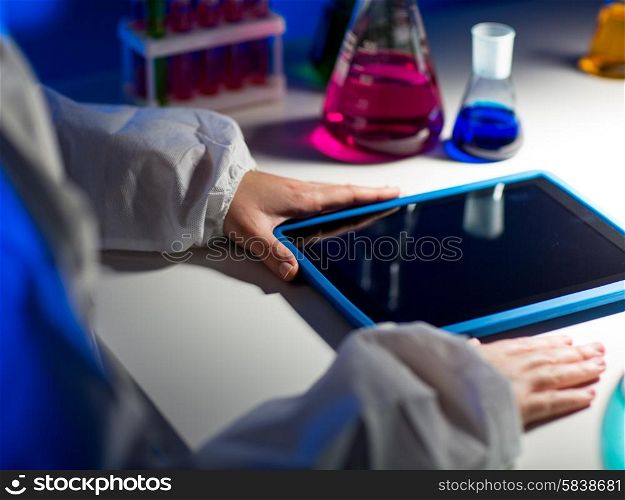 science, chemistry, medicine, technology and people concept - close up of young scientist with tablet pc computer making test or research in laboratory