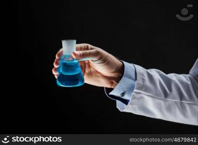 science, chemistry, research and people concept - close up of scientist hand holding test flask with chemical over black background