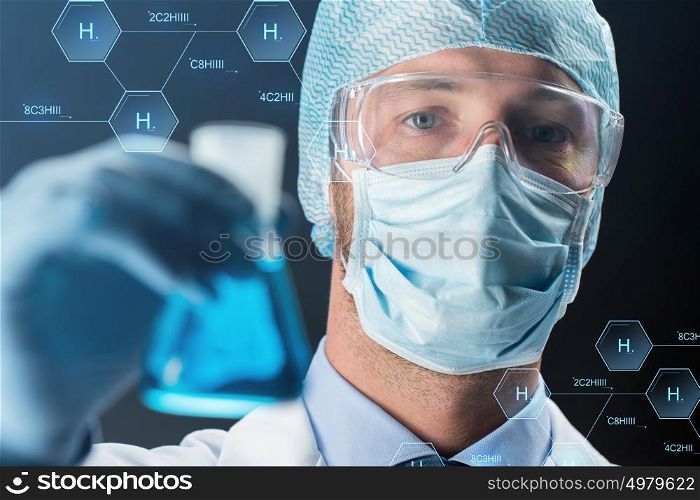 science, chemistry, research and people concept - close up of young scientist in protective mask, hat and goggles holding test flask with chemical over black background. close up of scientist holding flask with chemical