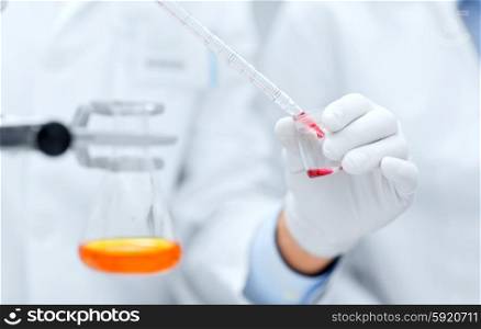 science, chemistry, technology, biology and people concept - close up of scientists hands with pipette filling test tube making research in clinical laboratory