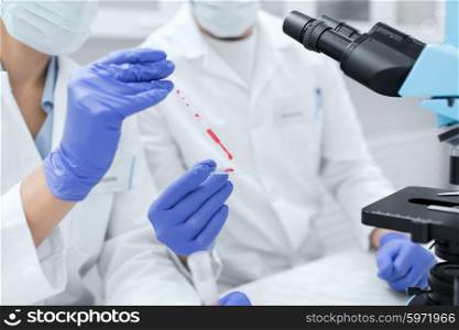 science, chemistry, technology, biology and people concept - close up of scientists hands with pipette and petri dish making research in clinical laboratory