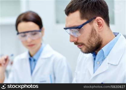 science, chemistry, technology, biology and people concept - close up of young scientists at laboratory